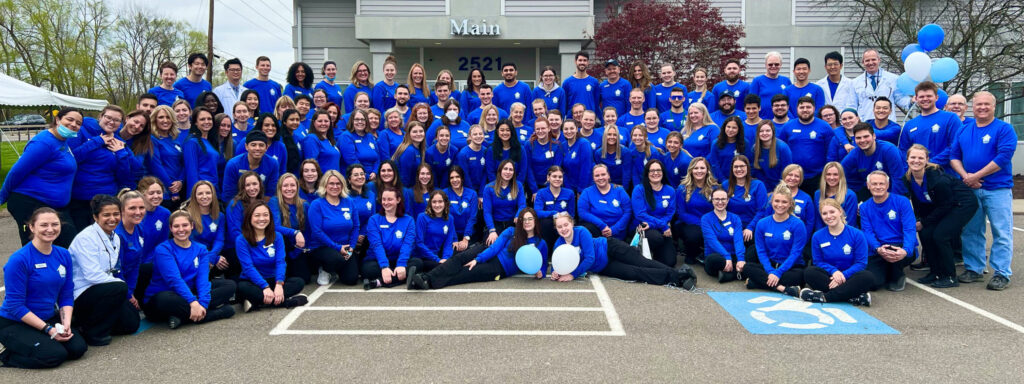 Large group staff photo in front of Vestal Office with balloons